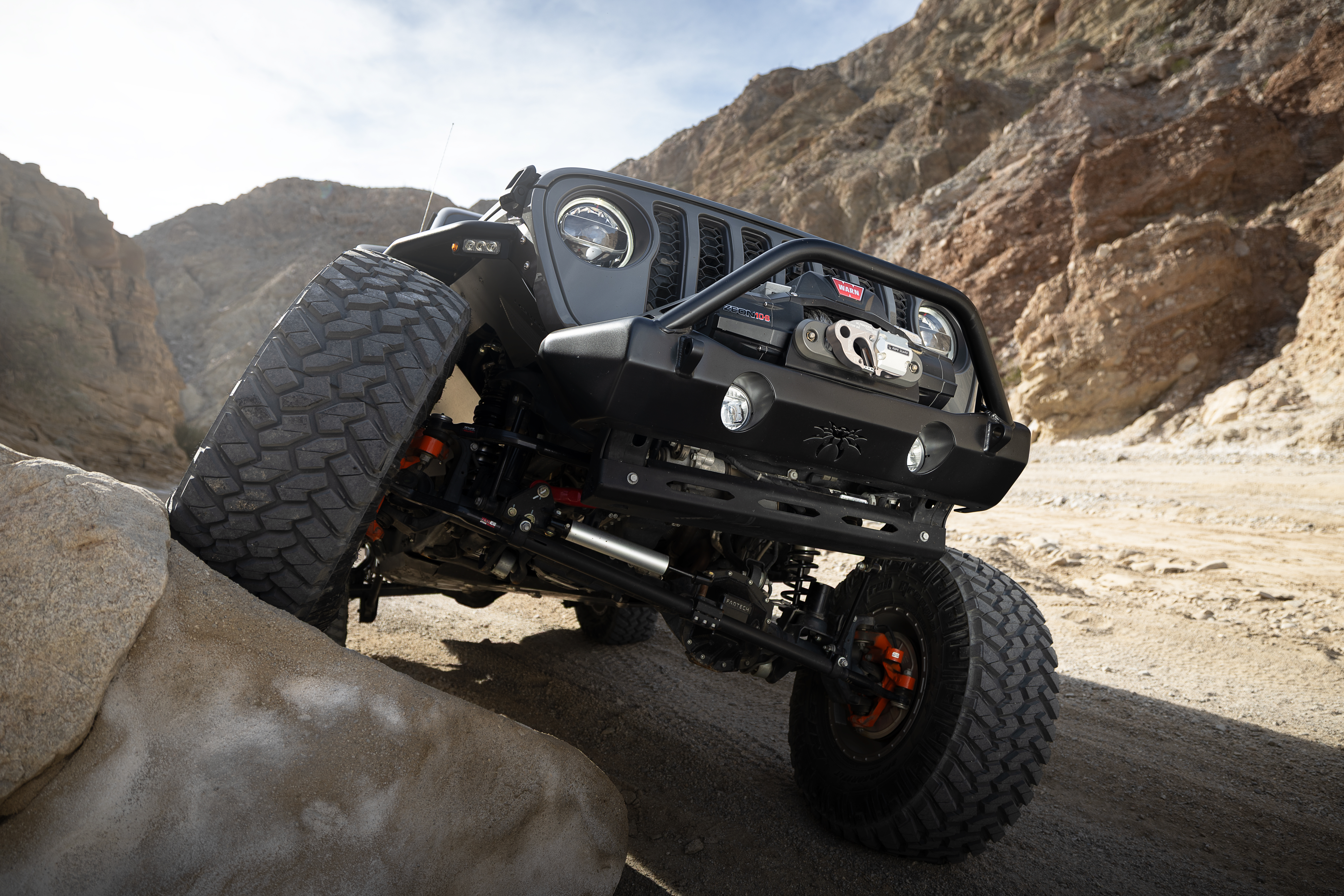Poison Spyder Nightshade JL Wrangler Rubicon flexing over rocks showing Fabtech suspension and 37-inch tires