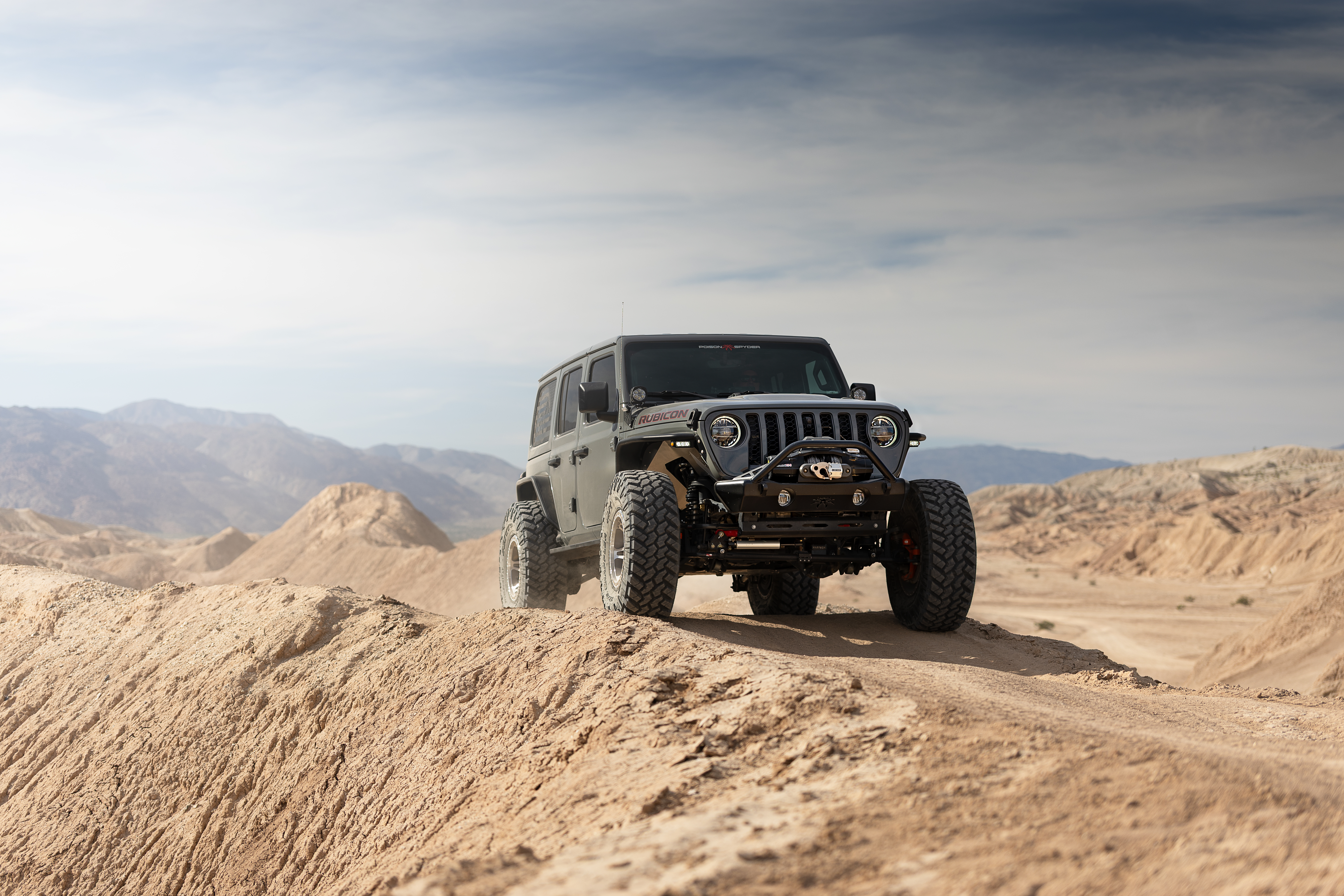 Poison Spyder Nightshade Jeep Wrangler Rubicon parked in a rocky desert canyon