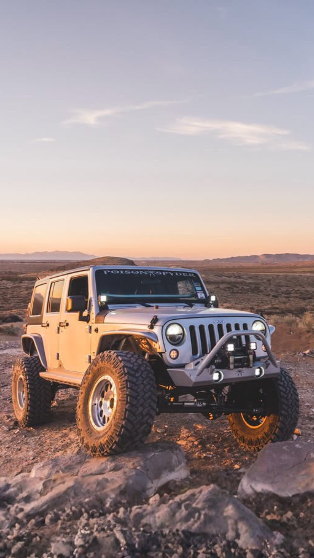 Poison Spyder Platinum Jeep Wrangler Unlimited Sport in silver with Poison Spyder windshield banner in the desert